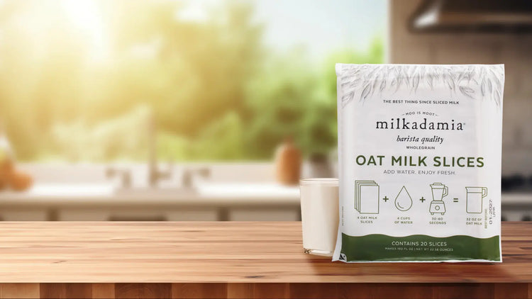 new oat milk slices - package next to glass of oat milk on kitchen counter